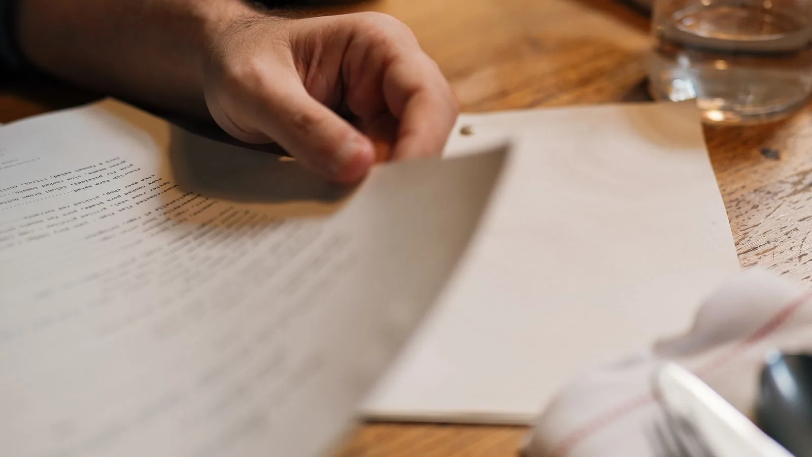 Mãos de uma pessoa lendo um documento sobre a mesa