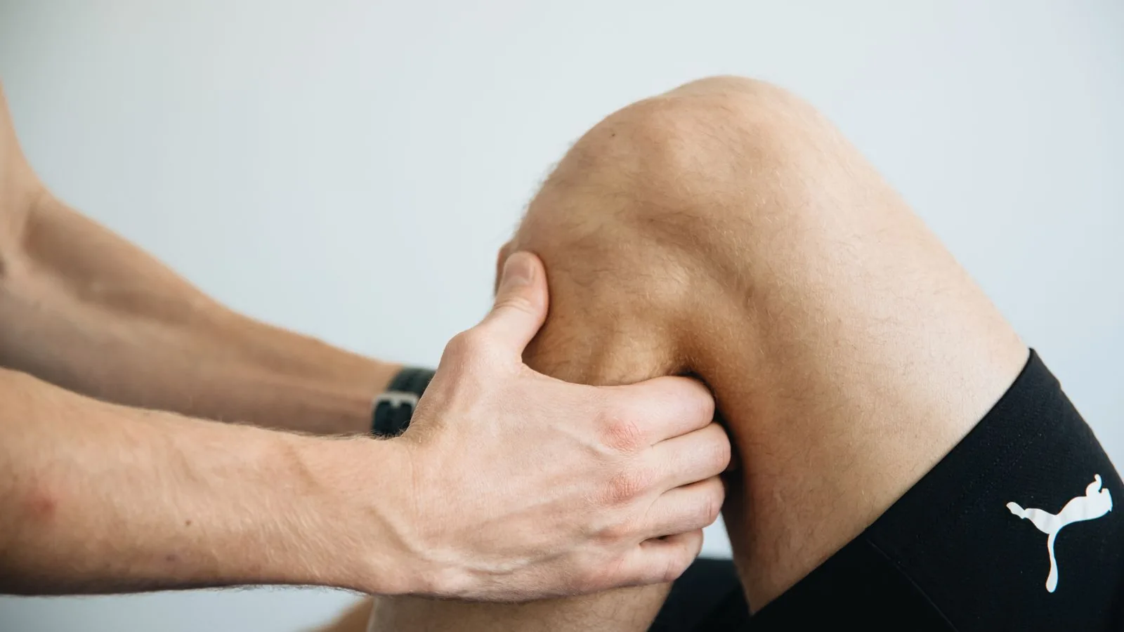 Fisioterapeuta avaliando o joelho de um paciente durante sessão de reabilitação